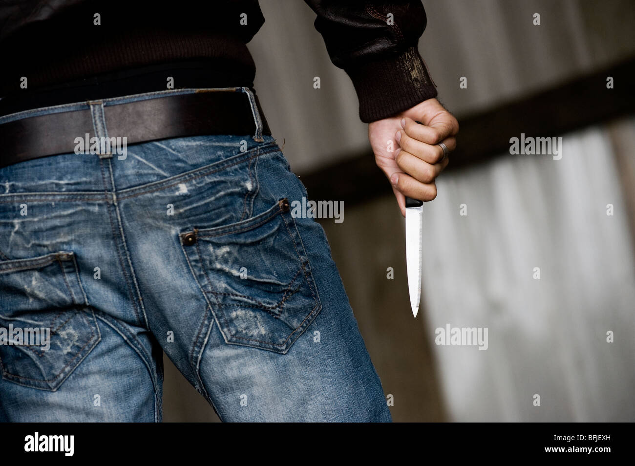 Rear view of a man carrying a knife. Stock Photo