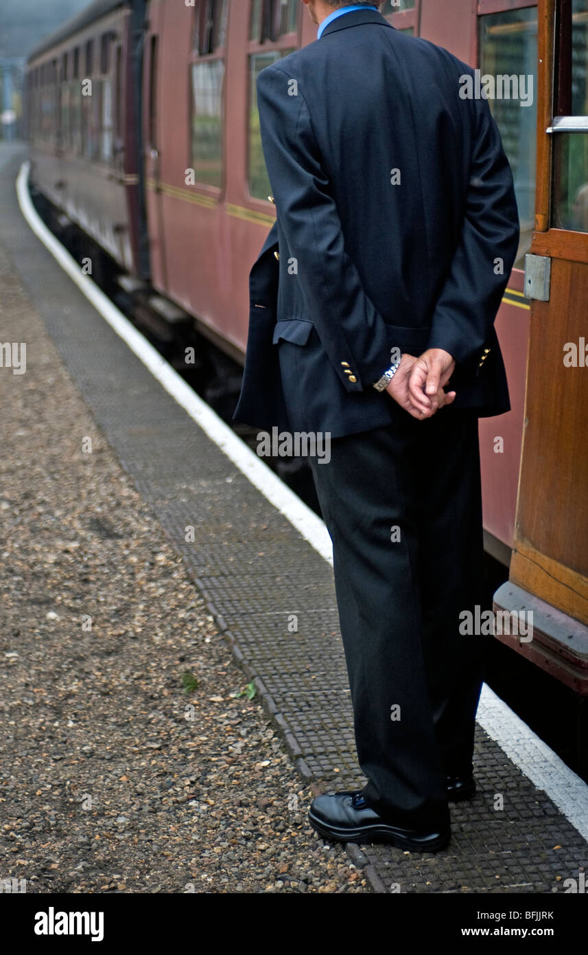 train guard standing with hands behind back waiting for time to despatch steam train Stock Photo