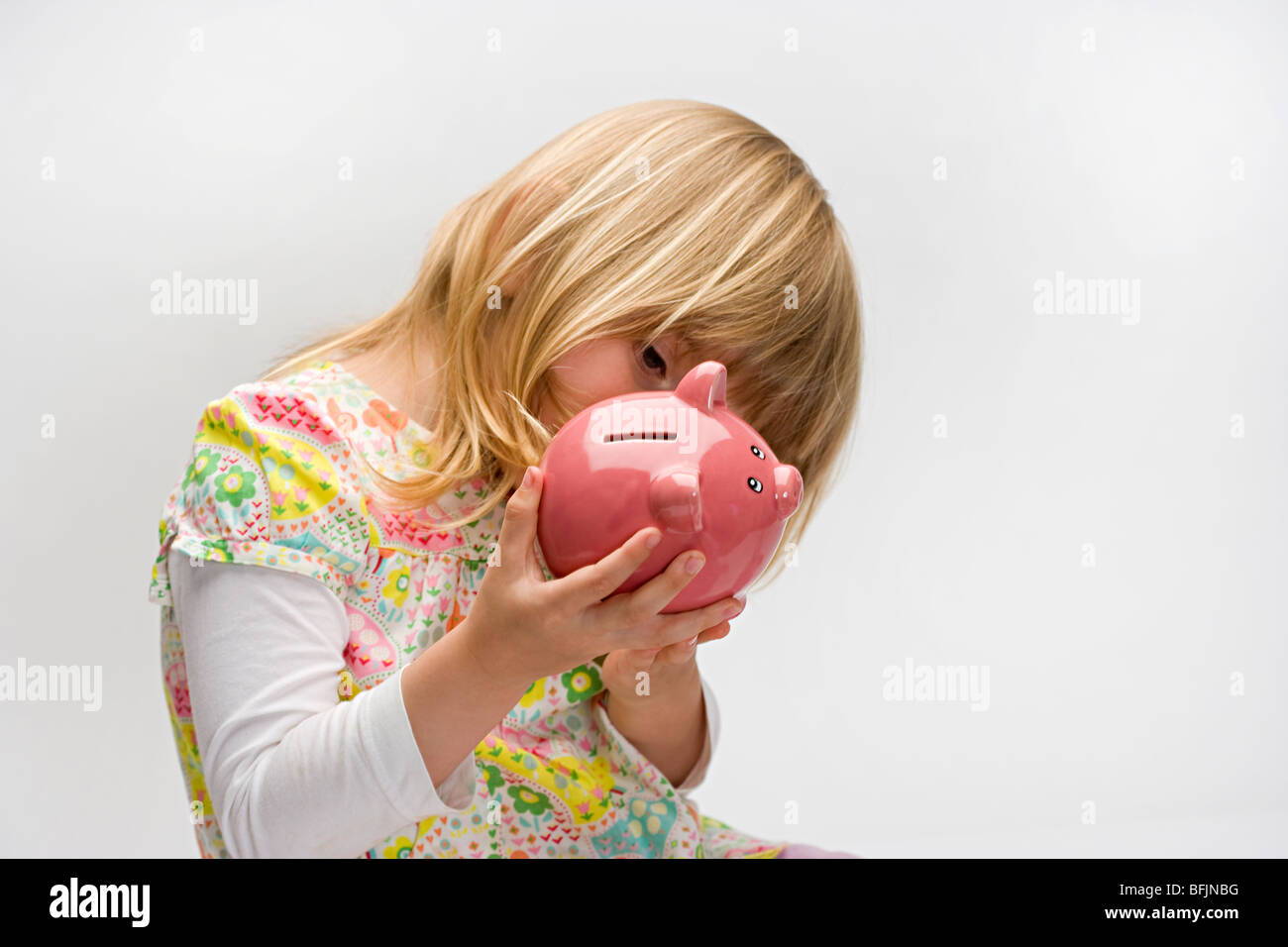young girl looking into a pink piggy bank Stock Photo