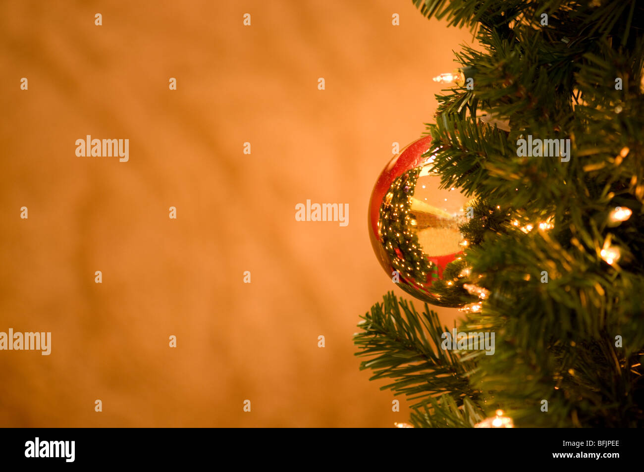 gold reflective ornament ball on a Christmas tree with gold background for copy space Stock Photo