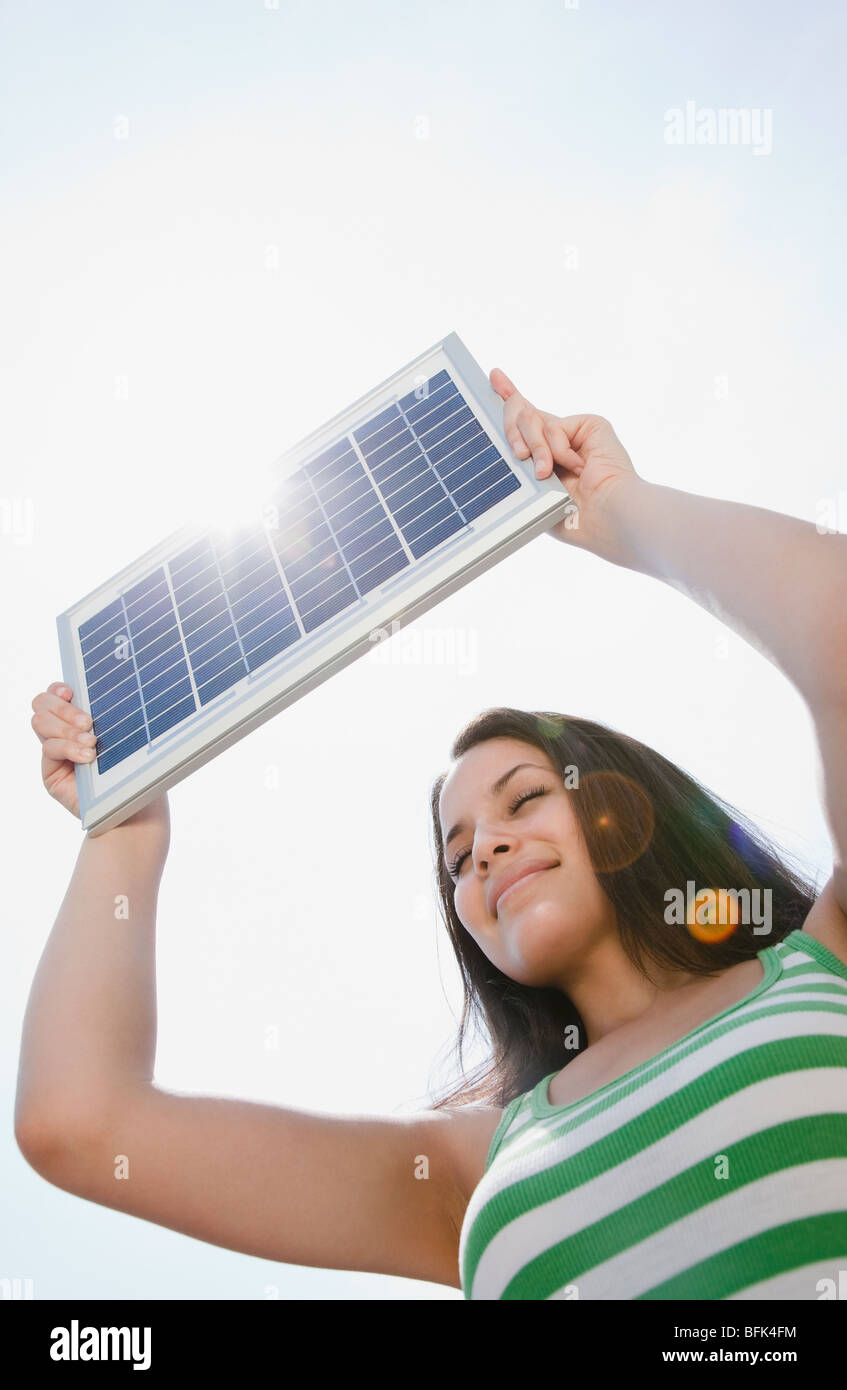 Mixed race woman holding solar panel Stock Photo