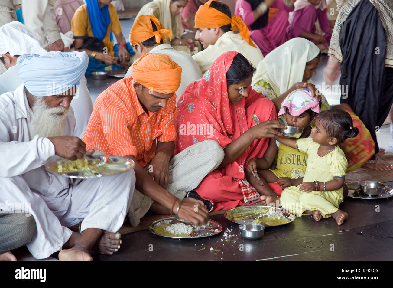 Indian family eating a thali (traditional indian meal). The Golden Temple free community dining room. Amritsar. Punjab. India Stock Photo