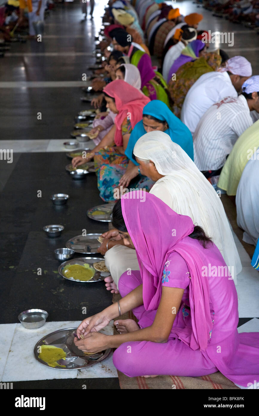 Indian women eating thali (traditional indian meal) Golden Temple free community dining room. Amritsar. Punjab. India Stock Photo