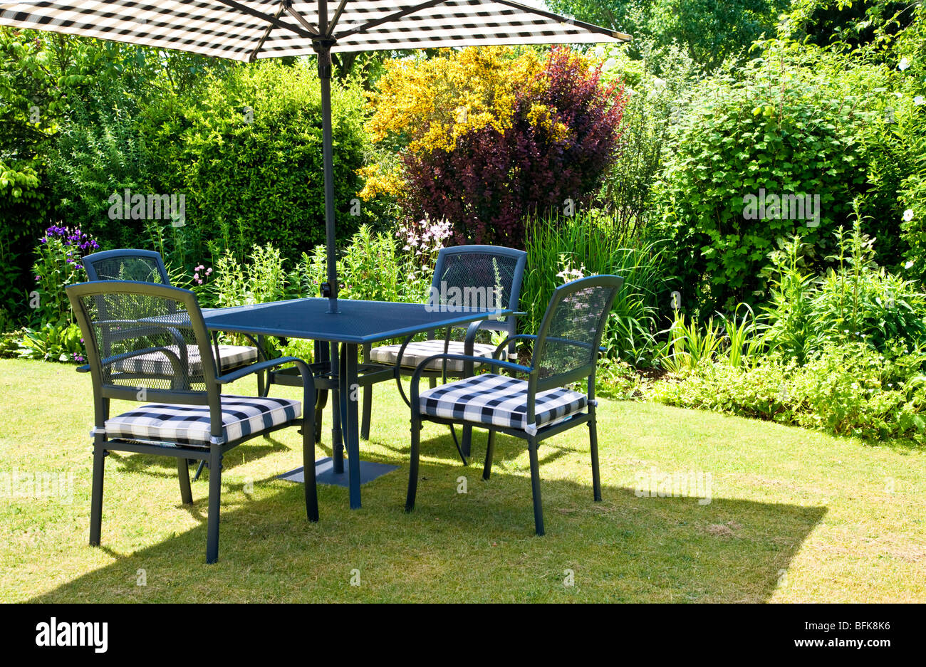 Contemporary garden furniture on the lawn in a typical English country or town garden on a sunny day in summer. Stock Photo