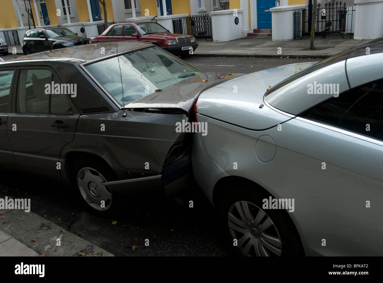 Two parked cars smashed together by another. Stock Photo