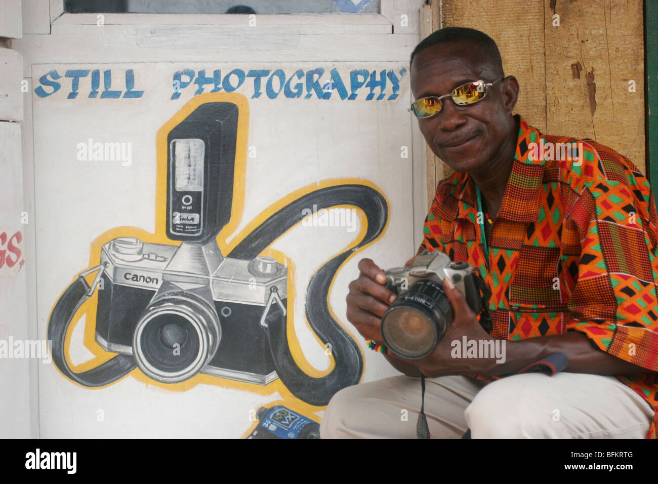 Kow Army Dauk aka Sanford poses for photographs outside his photography studio. Dixcove coastal town. Ghana. West Africa. Stock Photo