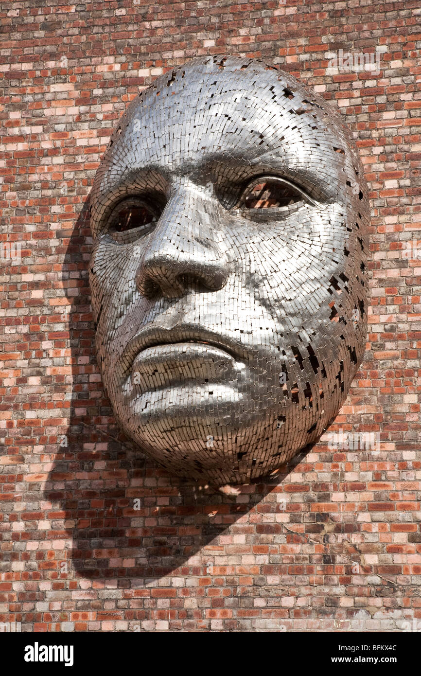 Metal face sculpture on outside wall of Lincoln City Drill Hall, by artist Rick Kirkby. Stock Photo