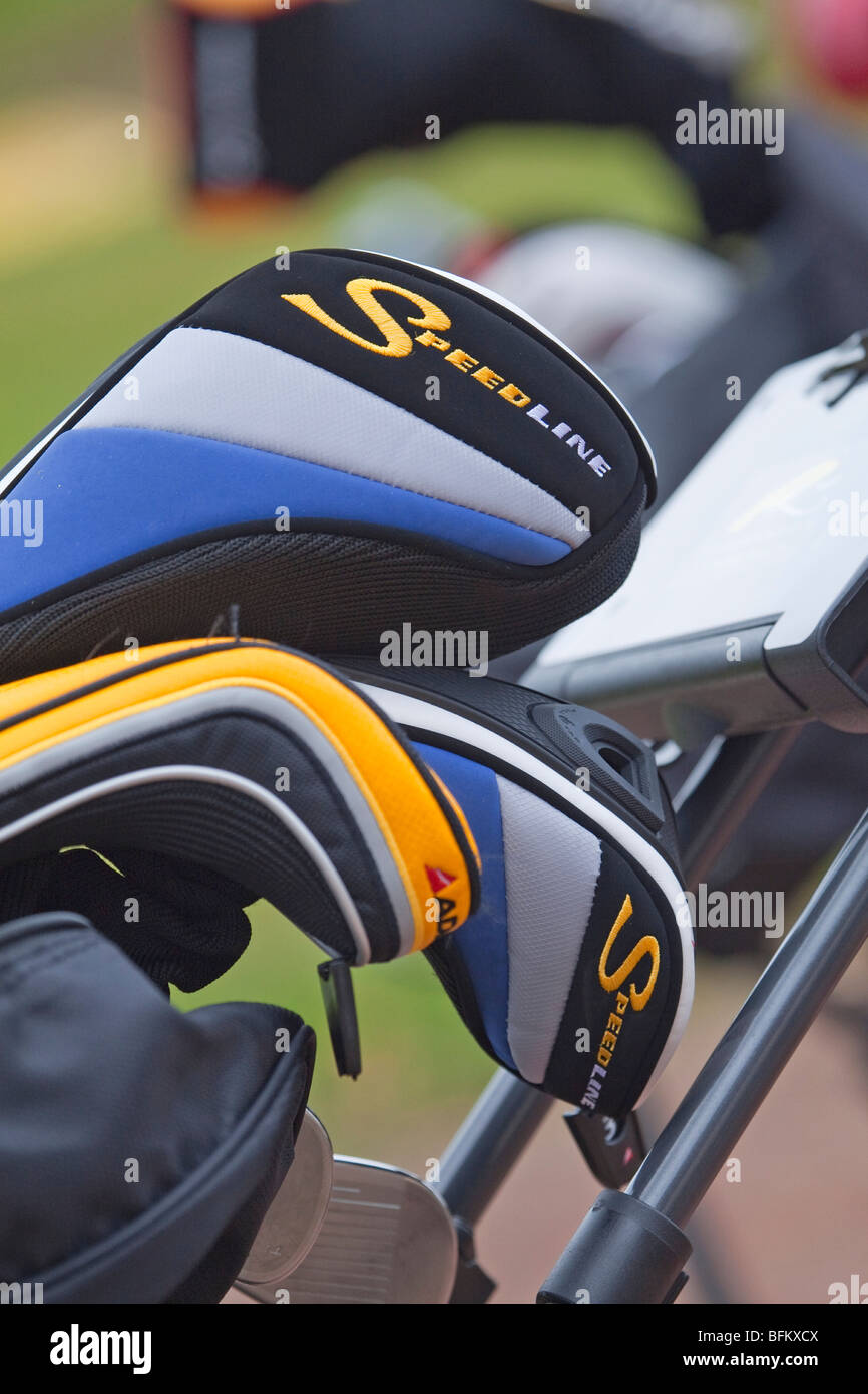 A close up photograph of golf clubs in a golf trolley showing woods in protective covers Stock Photo