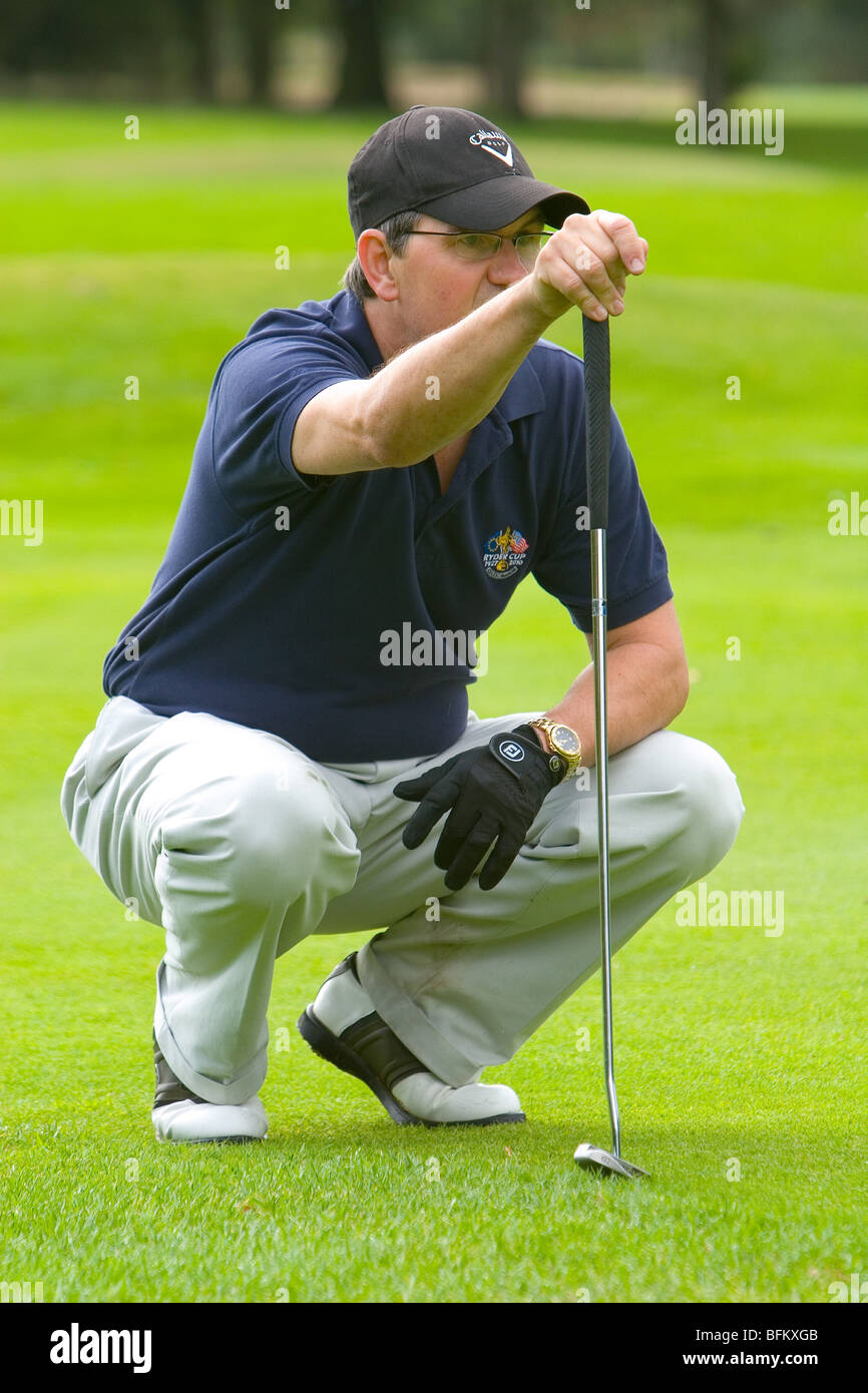 A middle aged white male preparing to line up his shot from the fairway while holding a club Stock Photo