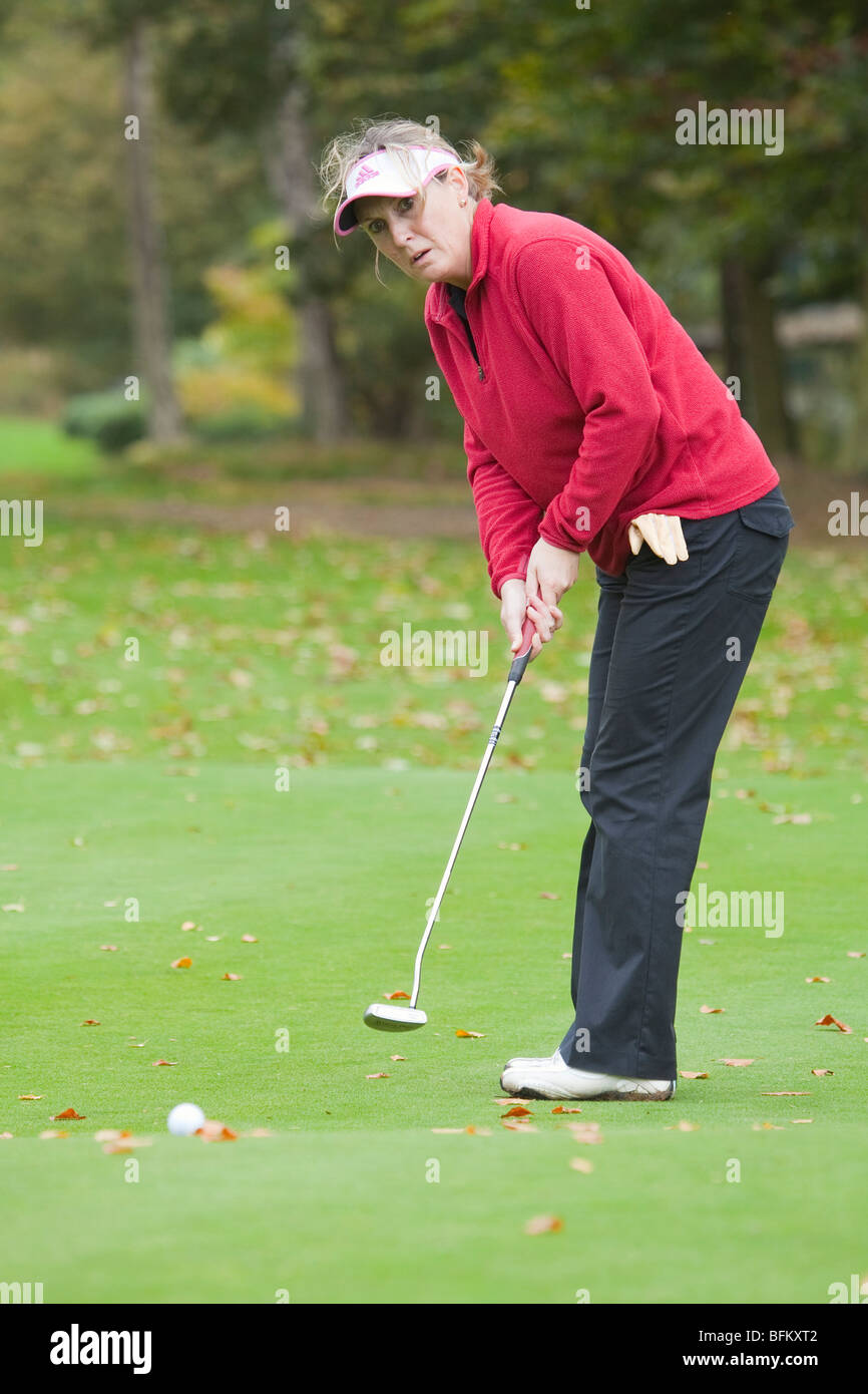 A middle aged white female golfer putting on the green Stock Photo