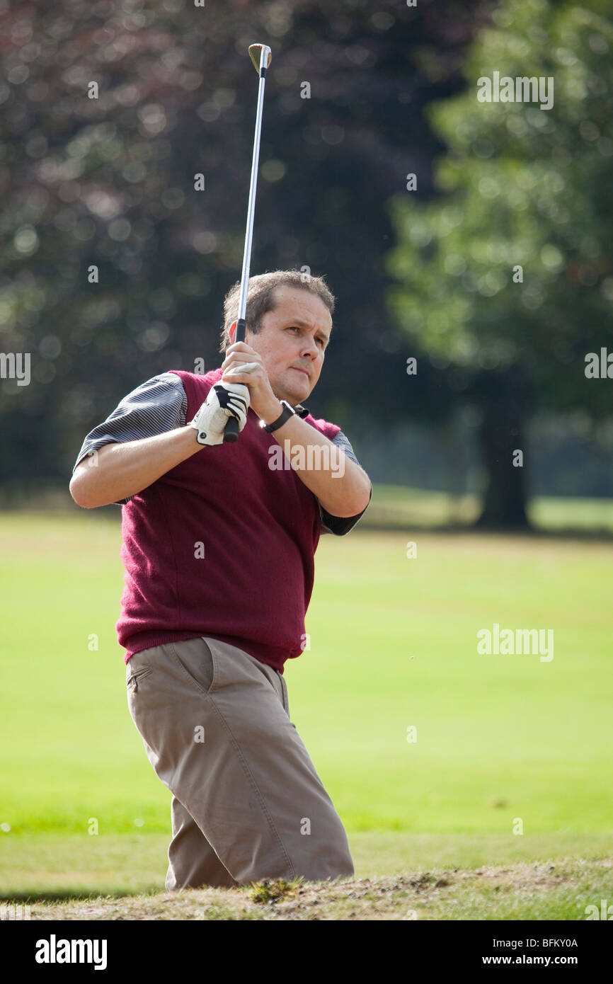 A white male playing golf and taking a shot from a sand bunker Stock Photo