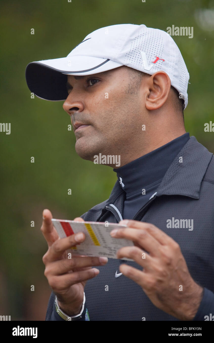 An Asian male checking distances on the course with his score card while playing golf Stock Photo