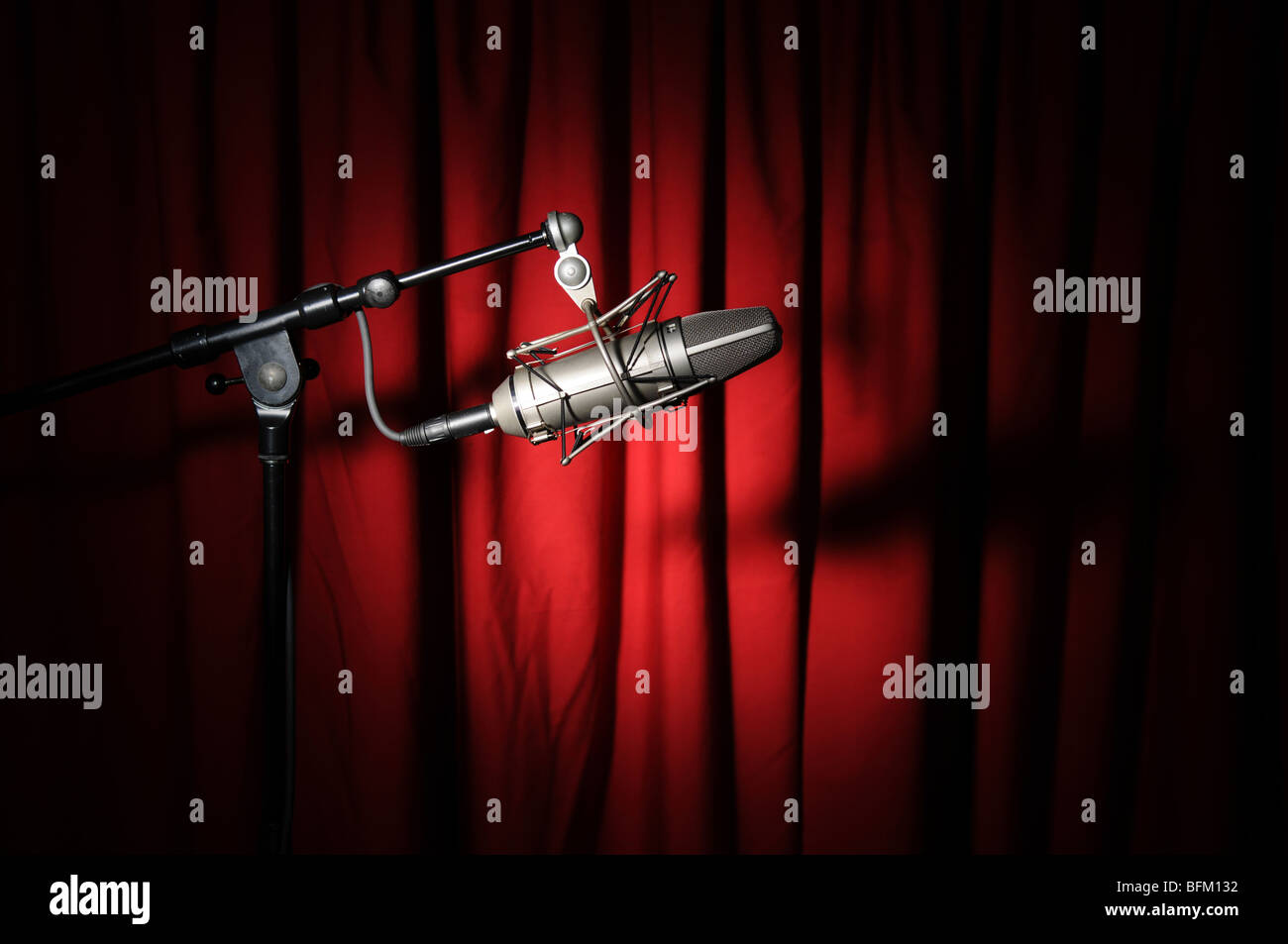Vintage microphone with spotlight over a red curtain Stock Photo