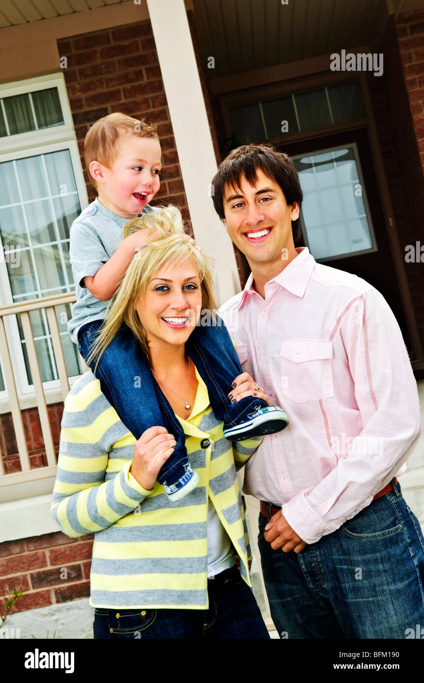 Young happy family standing in front of new home Stock Photo - Alamy
