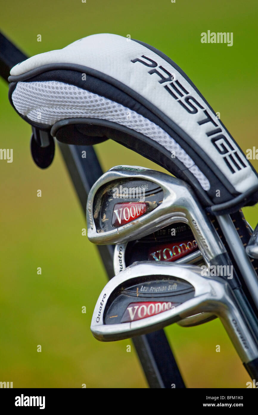 A close up photograph of golf clubs in a golf trolley showing irons and a wood in a protective cover Stock Photo