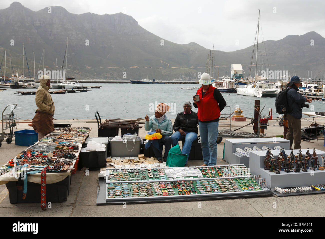 Open street market, fur seal boat trip offices, tourists and African sellers at Hout Bay, West Cape, South Africa, November 2009 Stock Photo