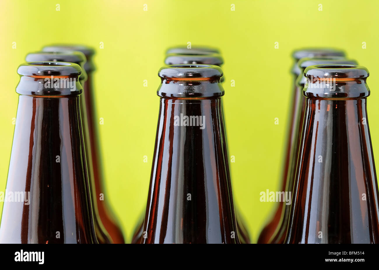 Empty beer bottles in rows in front of a bright green background Stock Photo