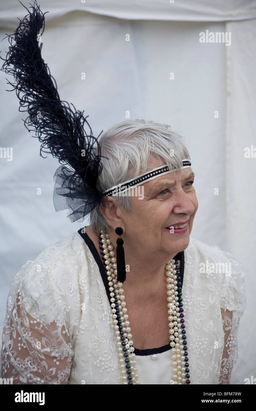 Lady in beautiful white twenties flapper costume with large black feather in head band. UK Stock Photo
