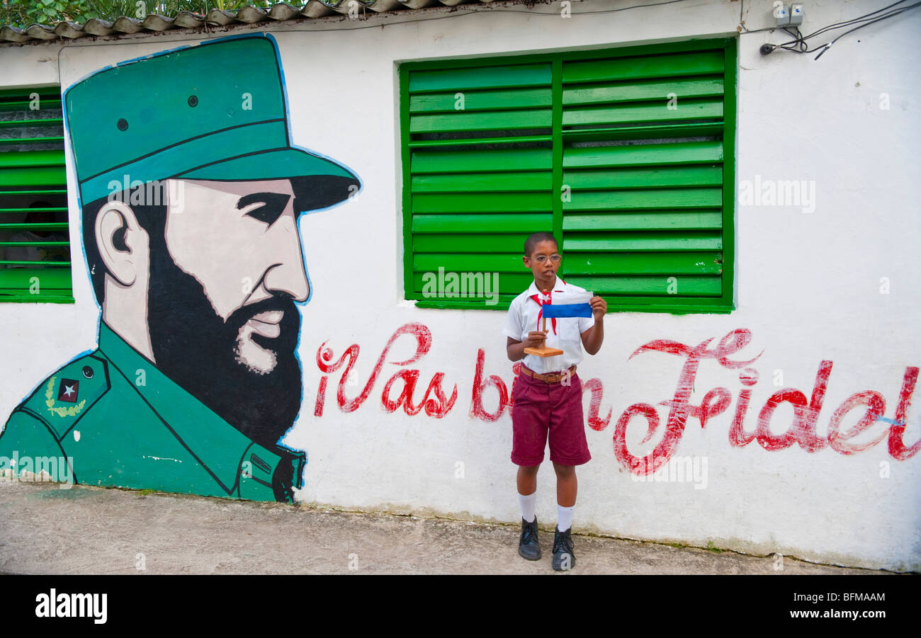 Schoolchild displays handmade flag in front of Castro wall painting at his school Stock Photo