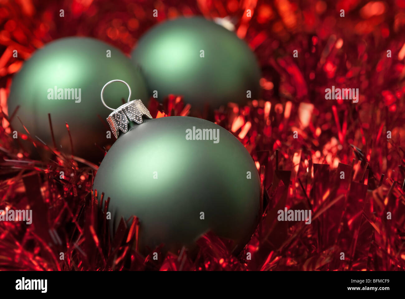 Green christmas ball on the red tinsel. aRGB. Stock Photo