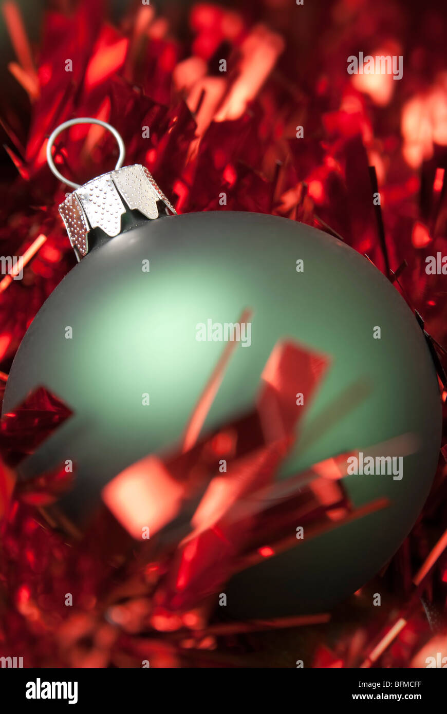 Green christmas ball on the red tinsel. aRGB. Stock Photo