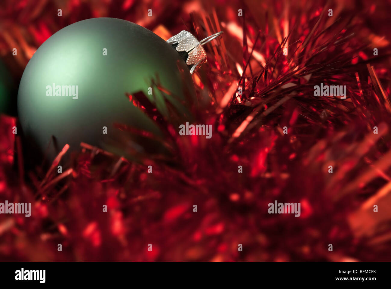 Green christmas ball on the red tinsel. aRGB. Stock Photo
