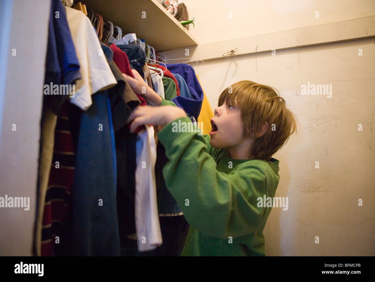 Seven year old selecting clothes to wear inside his closet in the morning Stock Photo