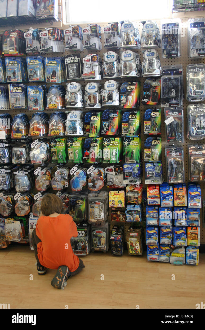Seven year old boy makes a selection from a large selection of action figure and star wars toys at a toy store, New Mexico, USA Stock Photo