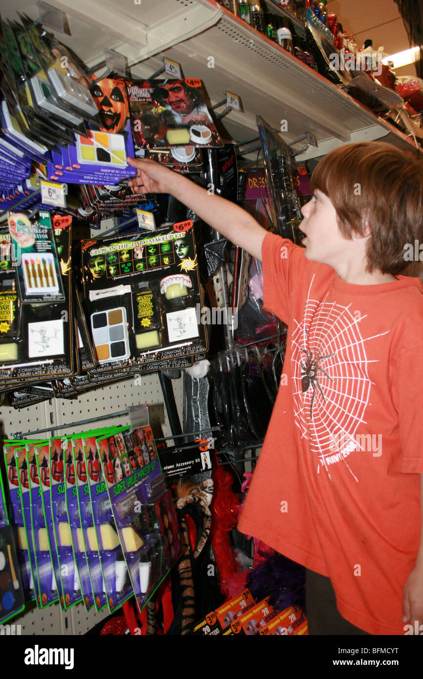 seven year old boy selecting Halloween costume and make up in a store, United States Stock Photo
