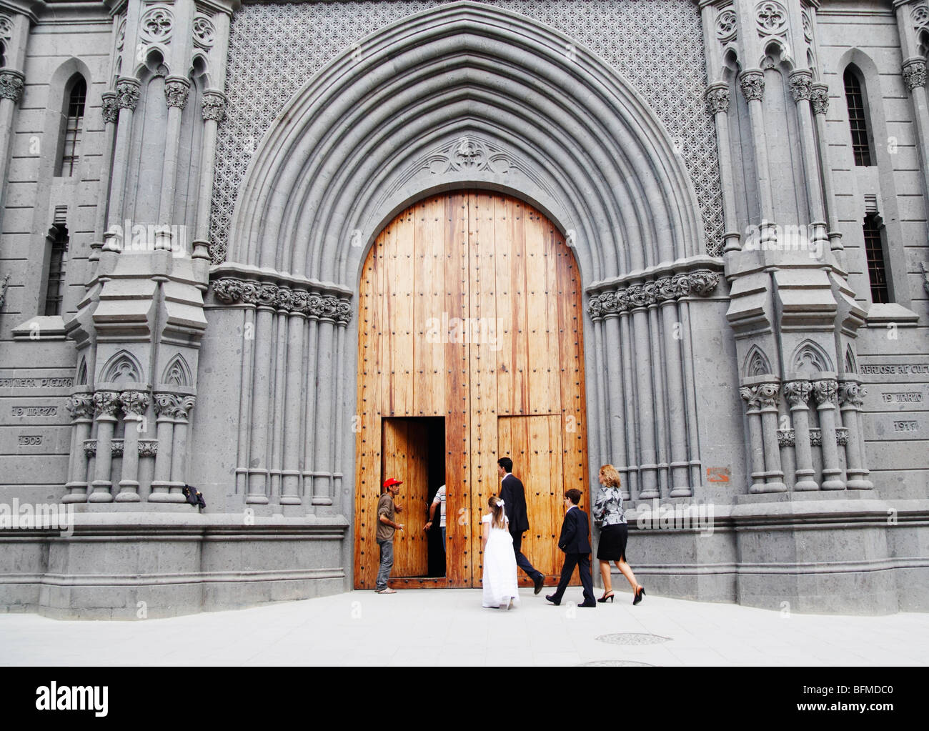 Young Spanish girl in first communion dress entering church with family. Stock Photo
