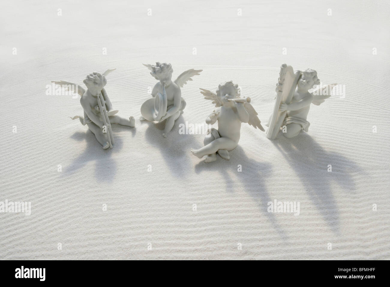 Angel figurines with musical instruments on white sand Stock Photo - Alamy