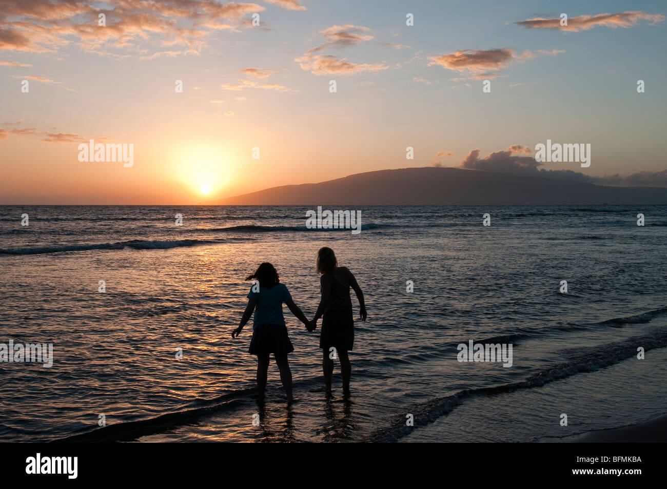 Mother and daughter looking at the sunset over the island of Lanai from west Maui Stock Photo