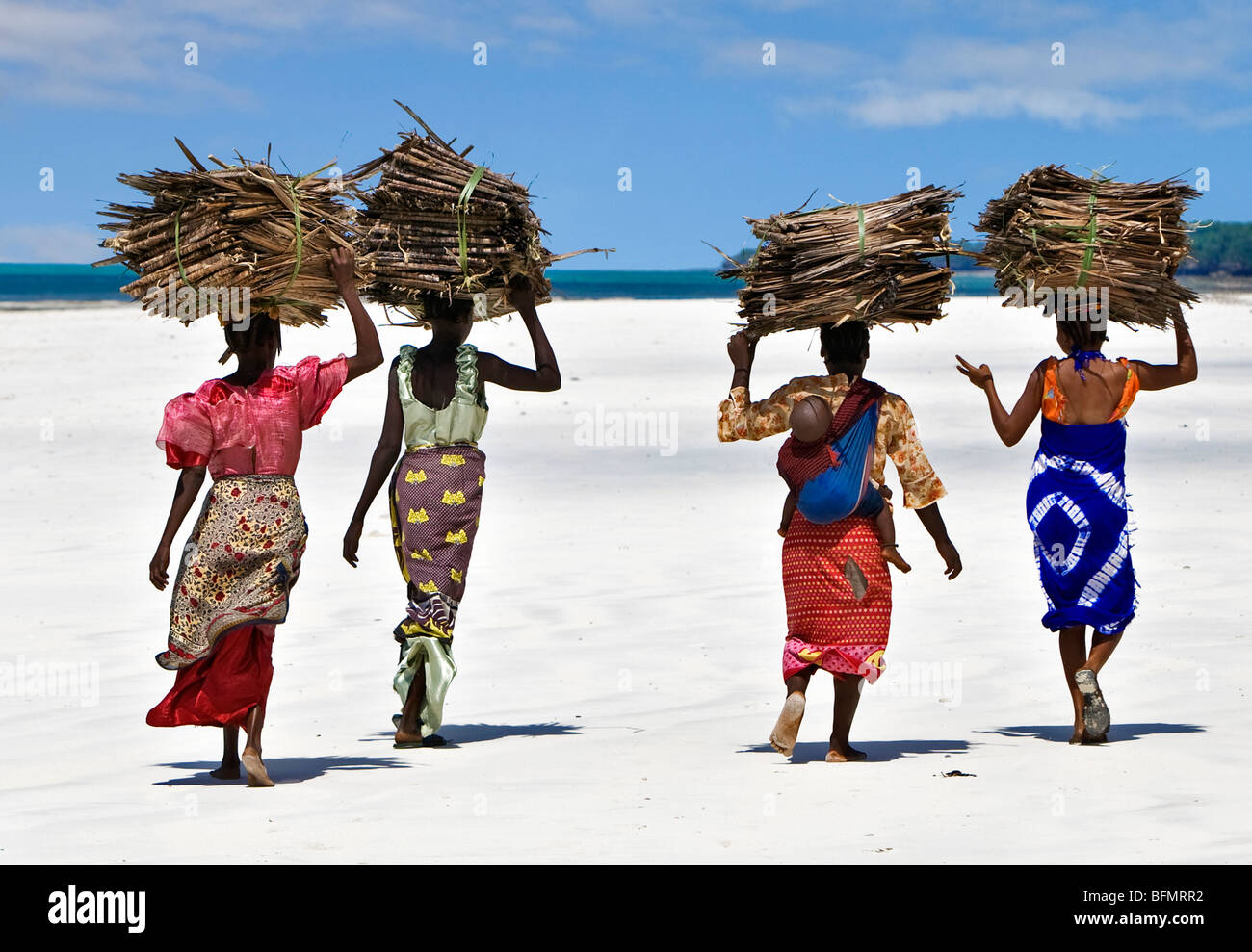 Kenya Mombasa. Women carry on their heads makuti (dried coconut palm fronds used as roofing material) on Kenya s south coast. Stock Photo