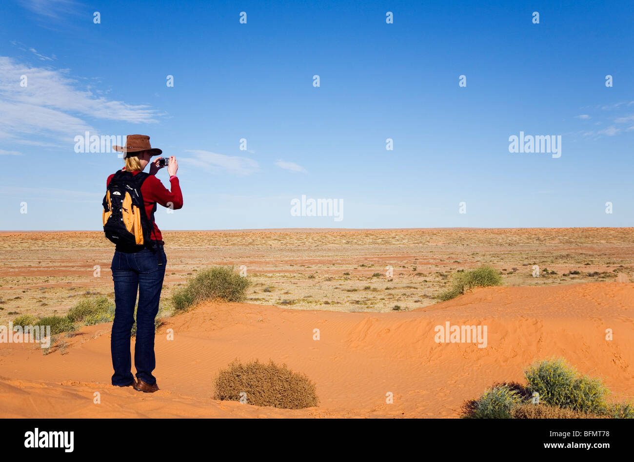 Australia, Queensland, Simpson Desert National Park, Birdsville. A woman looks over the Simpson Desert from a sand dune. (MR) Stock Photo