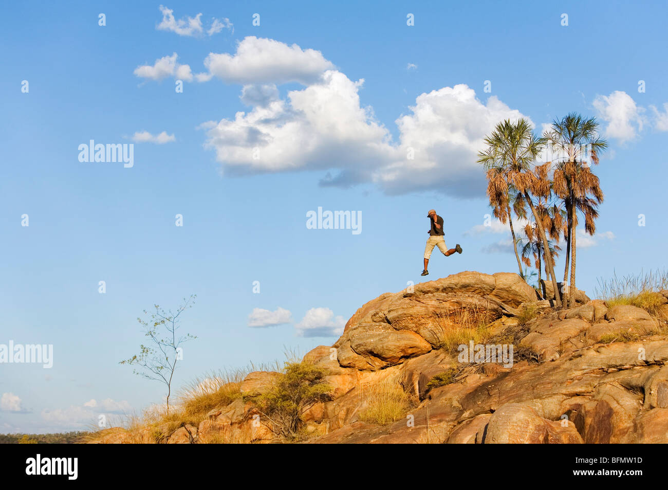 Australia, Northern Territory, Katherine.  A hiker leaps across rocks in Nitmiluk (Katherine Gorge) National Park.  (MR) Stock Photo