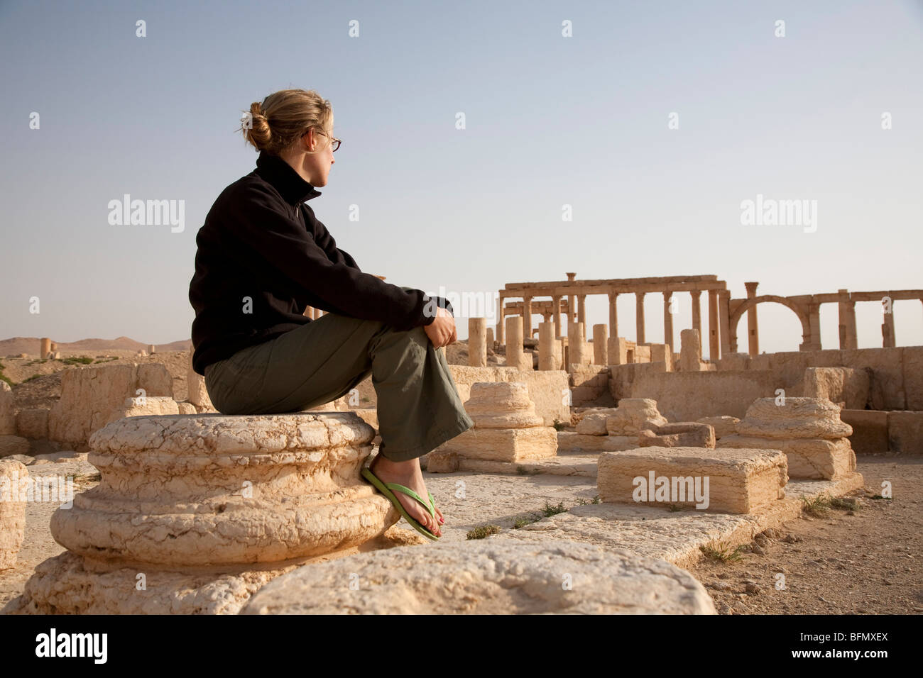 Syria, Palmyra. A tourist sits amongst the ancient ruins of Queen ...
