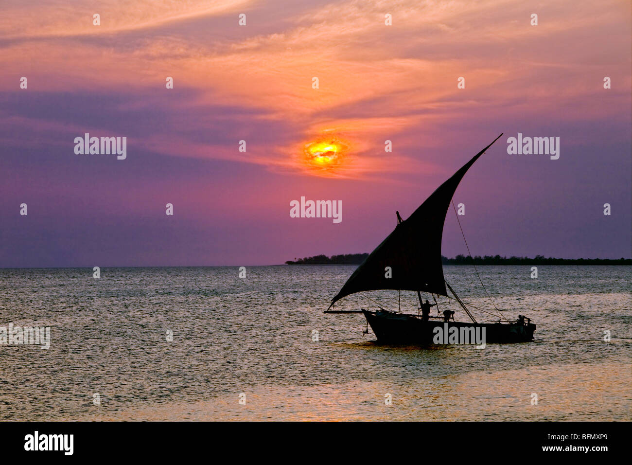 Tanzania, Zanzibar. A dhow sails back to Zanzibar harbour at sunset. Stock Photo