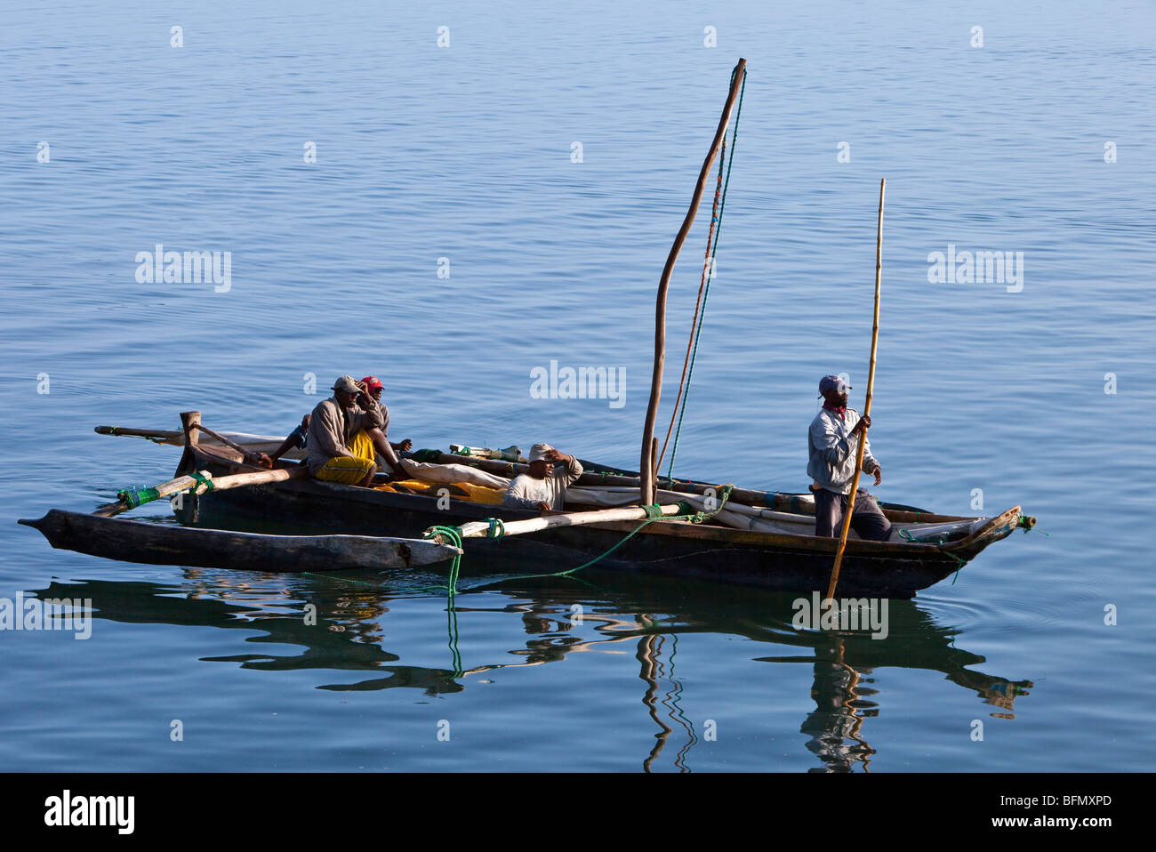 Tanzania, Zanzibar. In the morning, fishermen pole an outrigger canoe back to Zanzibars dhow harbour after fishing all night. Stock Photo