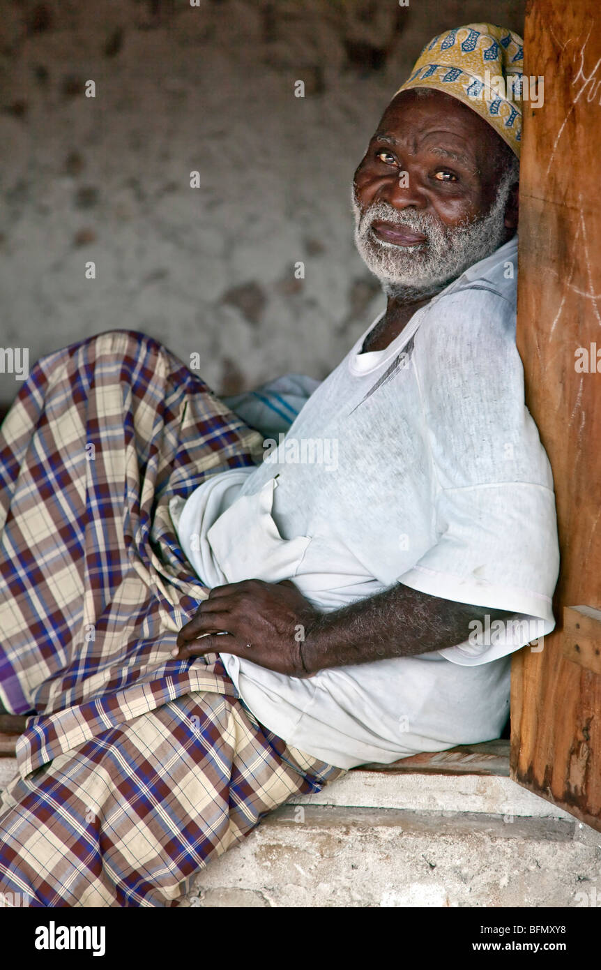 Tanzania, Zanzibar. An old man rests during the heat of the day at the entrance to his house in Nungwi. Stock Photo