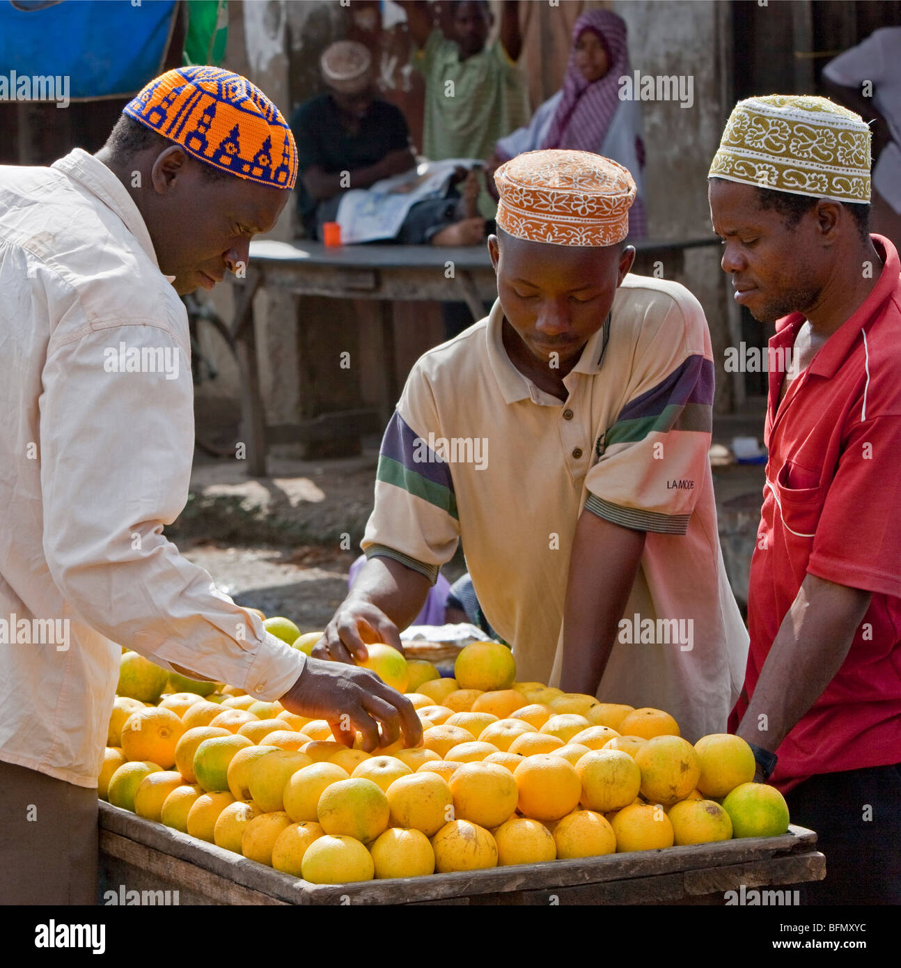 Tanzania, Zanzibar. Shoppers select locally-grown oranges from a stall at Mkokotoni Market in the northwest of Zanzibar Island. Stock Photo