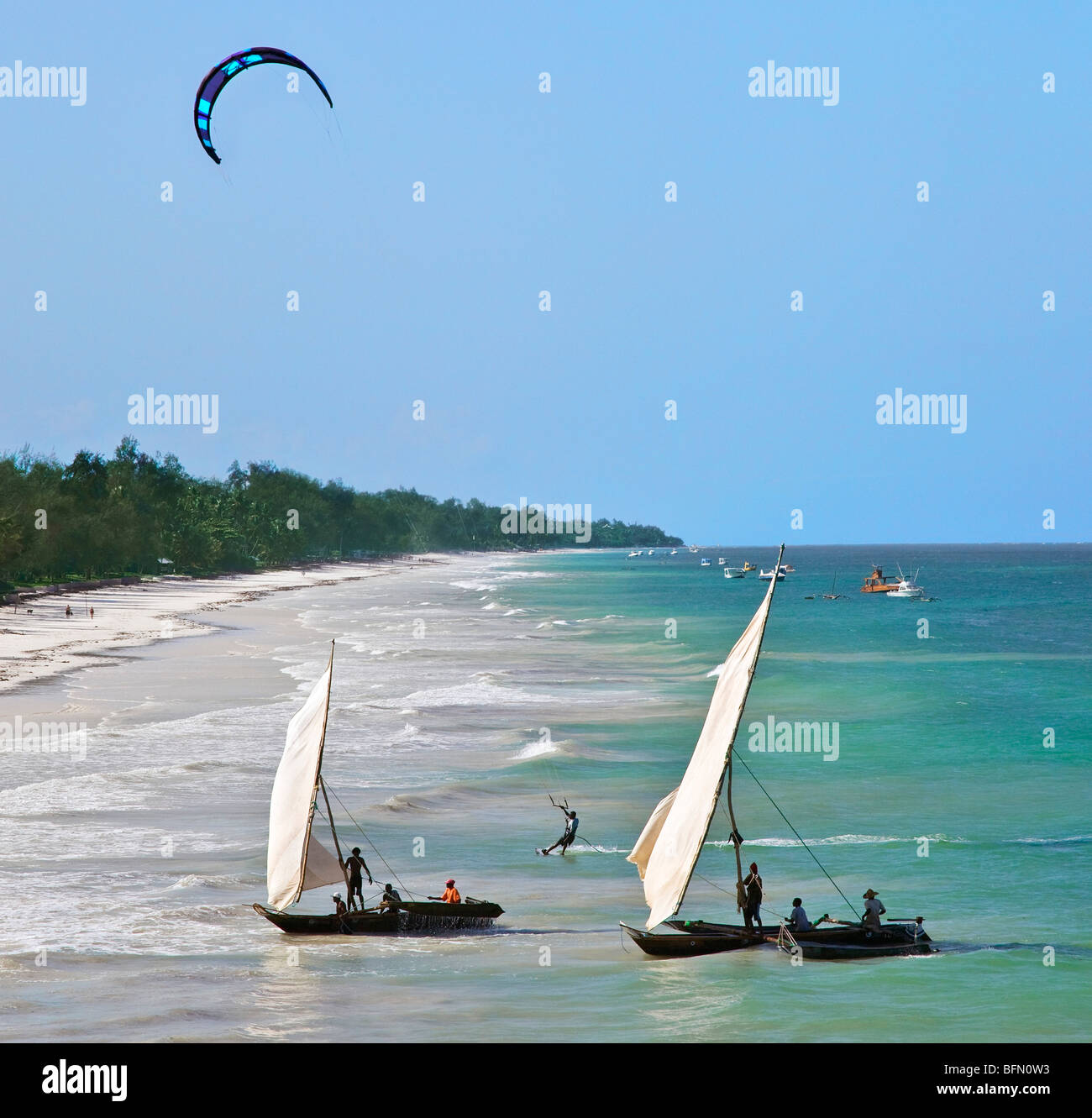 Kenya, Mombasa. A kite surfer and outrigger canoes beach at Diani Beach, a popular tourist destination on Kenya s south coast. Stock Photo