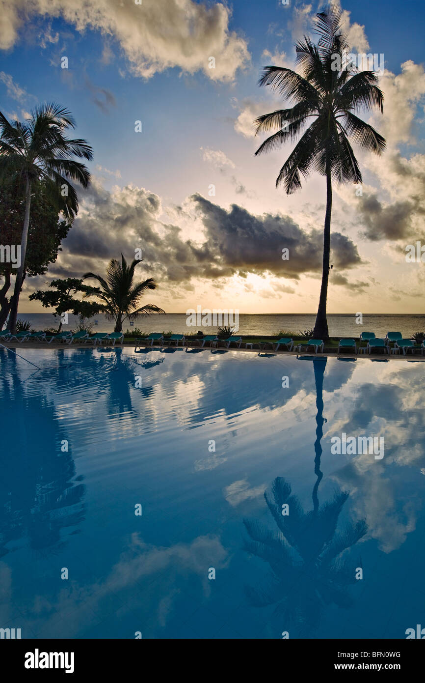 Kenya, Mombasa. The swimming pool of Baobab Resort at sunrise with the Indian Ocean in the distance. Stock Photo