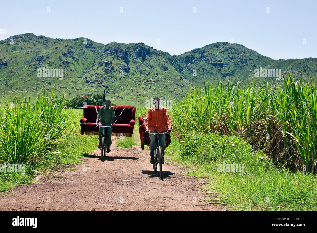 Kenya, Kisumu District. Two friends cycle home with a sofa set which they bought from a local furniture maker Stock Photo