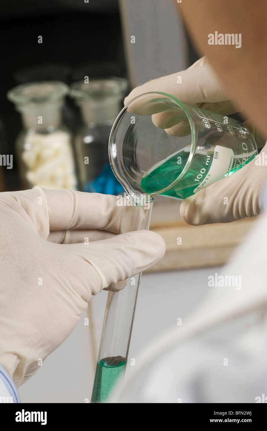 Scientist pouring green liquid in test tube Stock Photo