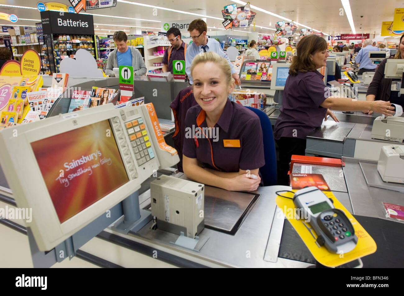 Sainsbury's supermarket. Smiling blonde girl in uniform at a checkout
