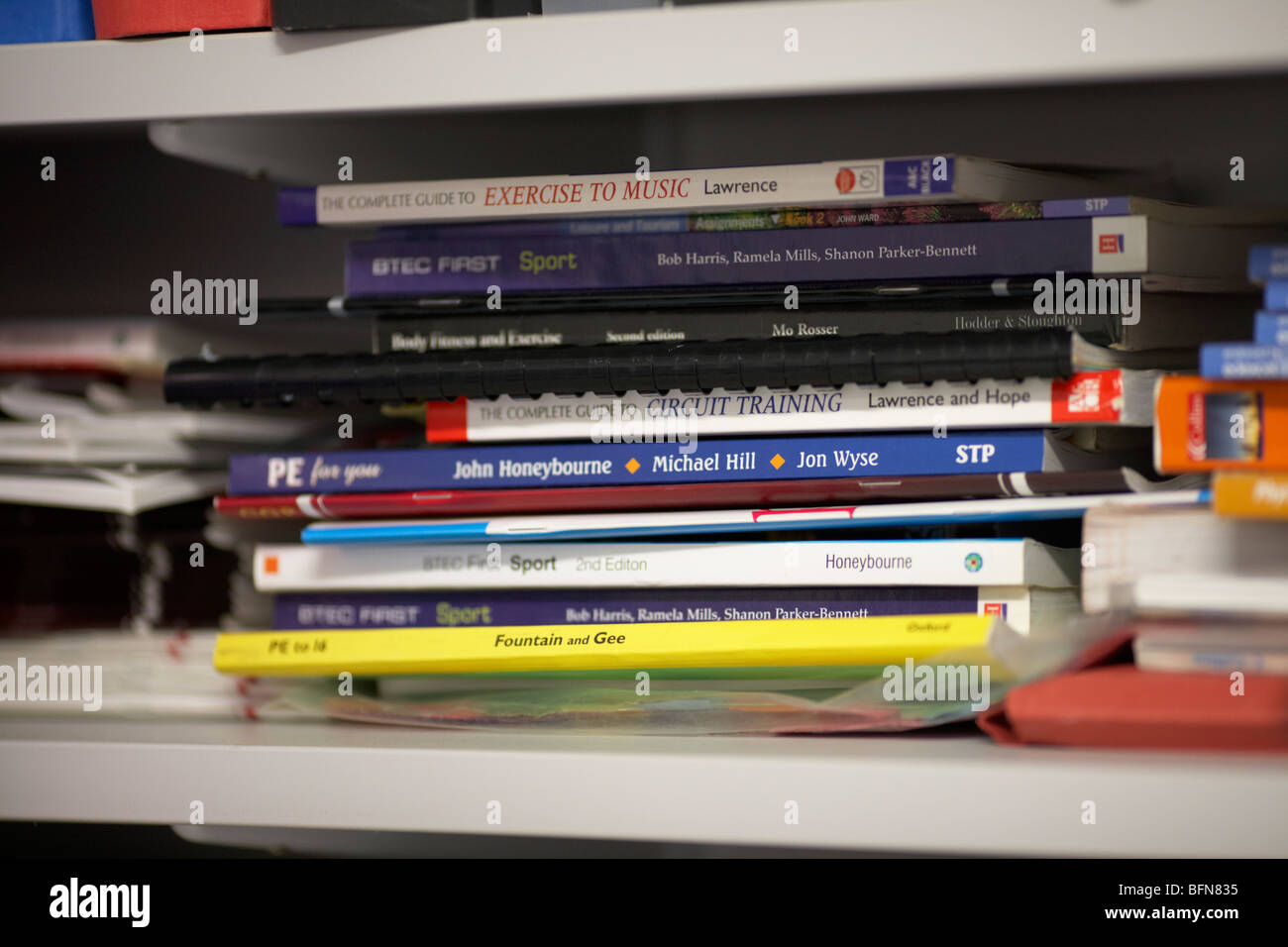 pile of sport and exercise textbooks on a shelf in a school PE department in the uk selective focus Stock Photo