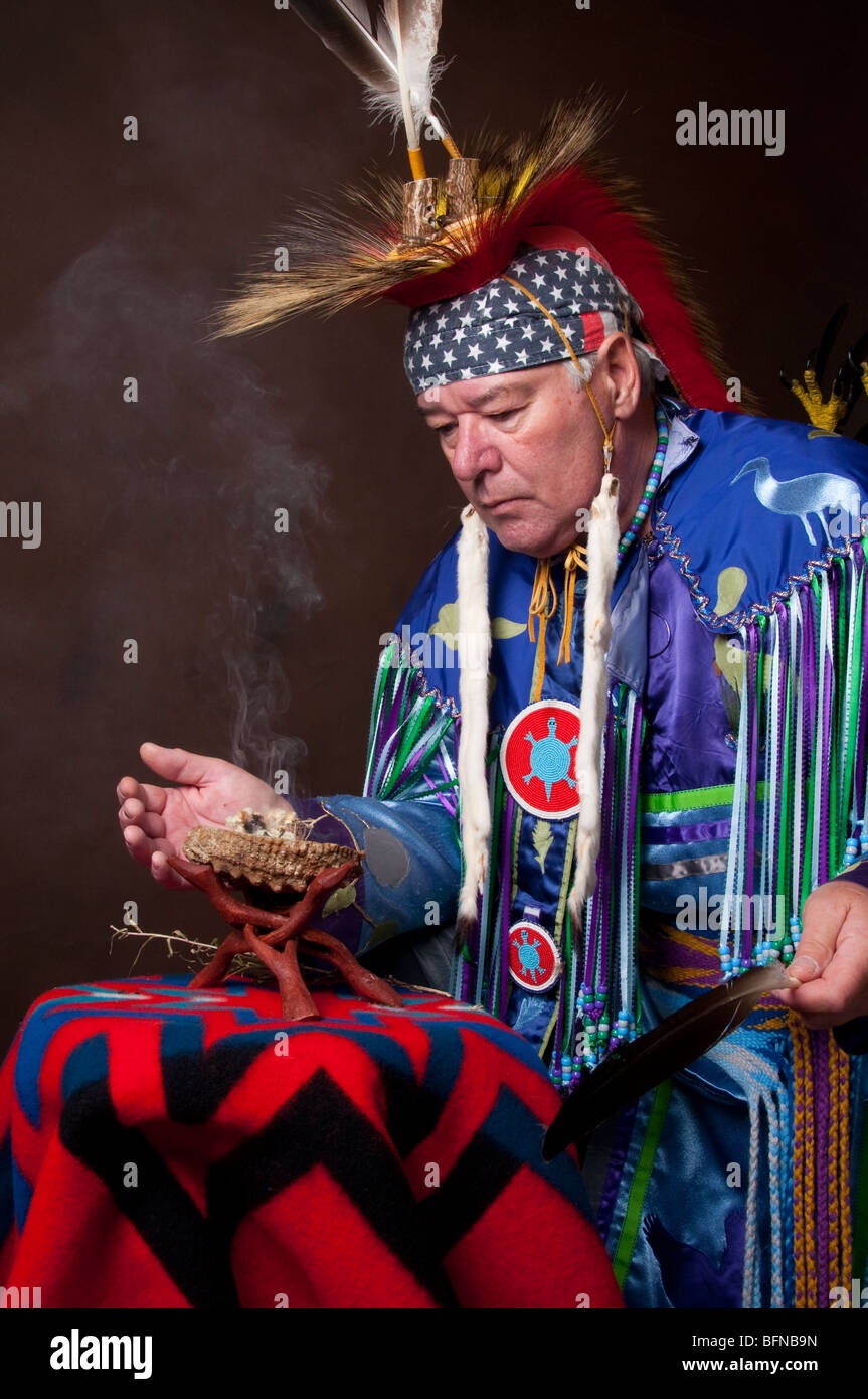 Native American Male in regalia performing a smudge ceremony on brown ...