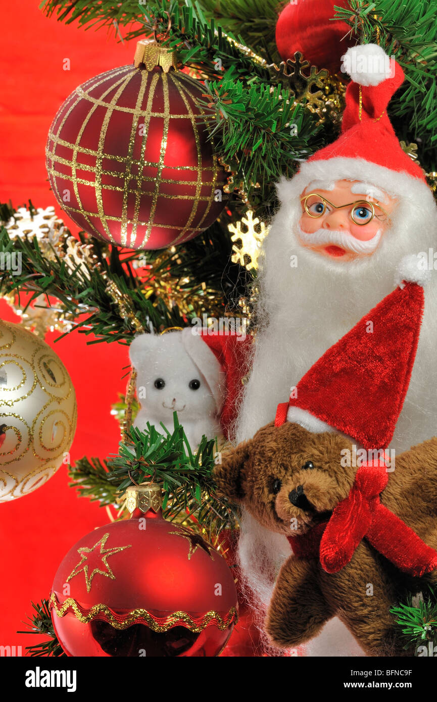 Santa Claus / Father Christmas, teddy bear and bells hanging in tree Stock Photo