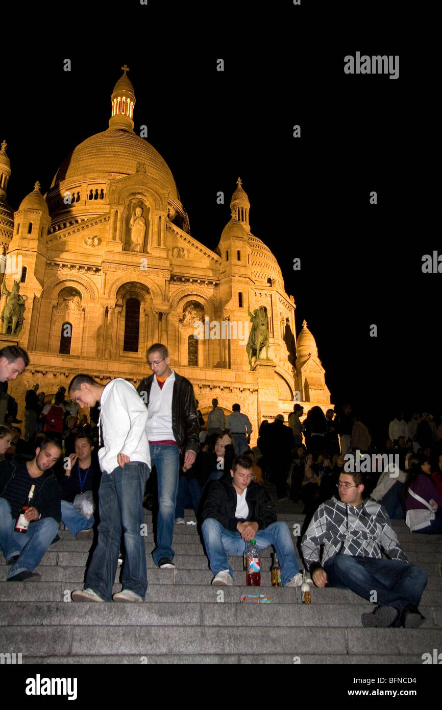People gather on the steps of the Sacre-Coeur Basilica at night in Paris, France. Stock Photo