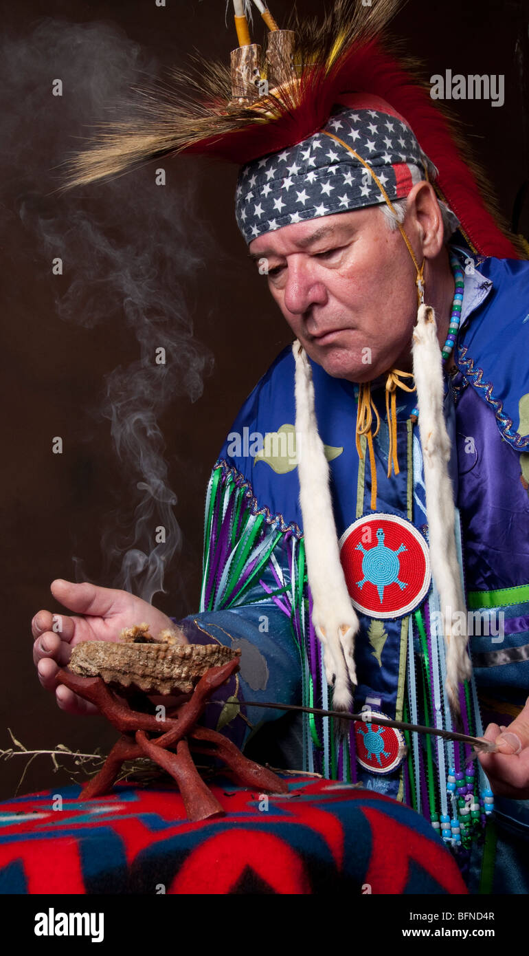 Native American Indian male in full regalia fanning burning sage in